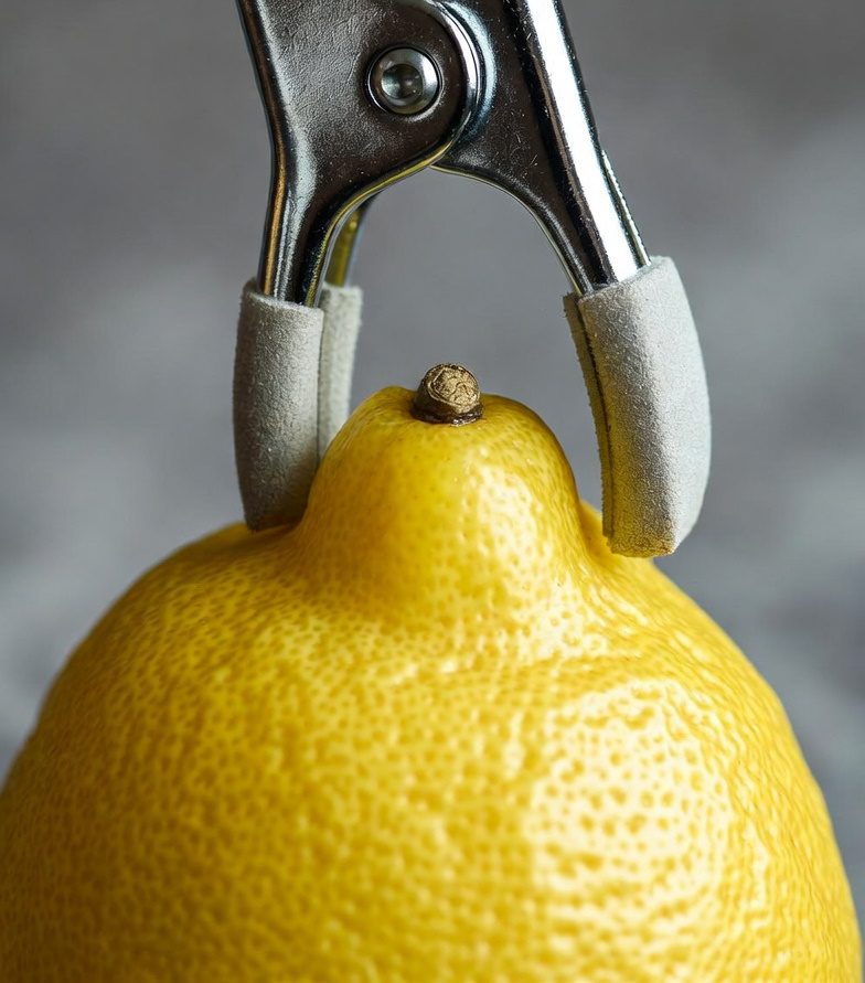 Una pinza para pezón apretando un limón.